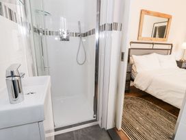 A bathroom with a shower and sink next to a bedroom with a bed and a striped rug at DownTown - Manhattan House in Llandudno