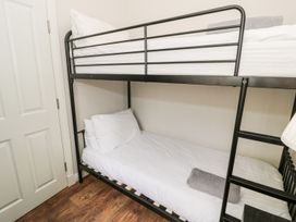 A bunk bed with white bedding and a gray towel in a room with a wooden floor at DownTown - Manhattan House in Llandudno