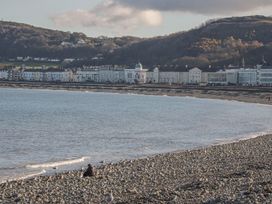 A rocky beach with water and seagulls near a row of buildings at DownTown - Manhattan House in Llandudno