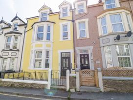 The front view of a row of terraced houses with different colored facades and small fenced front yards at MidTown - Manhattan House in Llandudno
