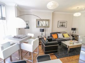 A living room with a gray sofa and white chairs around a dining table at MidTown - Manhattan House in Llandudno