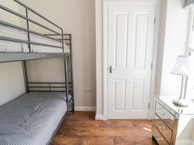 A room with a metal bunk bed a white door a mirrored nightstand and a lamp at MidTown - Manhattan House in Llandudno