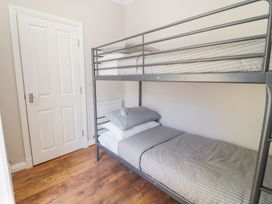 A bedroom with a metal bunk bed and striped bedding at MidTown - Manhattan House in Llandudno