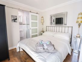 A bedroom with a bed made with white linens towels on the bed a bedside table with a lamp a mirror on the wall and a sliding door to a bathroom at MidTown - Manhattan House in Llandudno