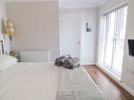A bedroom with a bed, folded towels on the bed, a lamp, a radiator, a door, a window with blinds, and a wall-mounted TV at MidTown - Manhattan House in Llandudno