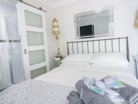 A bedroom with a double bed white bedding gray towels and toiletries a mirror above the bed and a door to an en suite bathroom at MidTown - Manhattan House in Llandudno