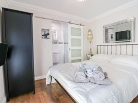 A bedroom with a bed and towels on it a black wardrobe and a bathroom visible through a sliding door at MidTown - Manhattan House in Llandudno