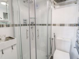 A bathroom with a glass shower enclosure a toilet a sink and a towel rack at MidTown - Manhattan House in Llandudno