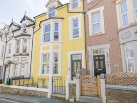 A row of terraced houses with yellow and brown facades and small fenced front yards at UpTown - Manhattan House in Llandudno