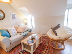 A living room with a sofa and a round chair on a multicolored rug at UpTown - Manhattan House in Llandudno