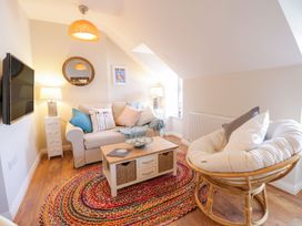 A living room with a sofa and a round chair with cushions a colorful rug and a coffee table at UpTown - Manhattan House in Llandudno