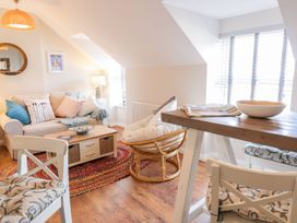 A living area with a sofa cushions a round wicker chair a wooden coffee table and dining chairs at UpTown - Manhattan House in Llandudno
