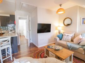 A living room with a sofa pillows coffee table and a wall mounted TV at UpTown - Manhattan House in Llandudno