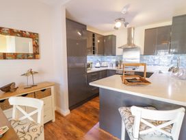 A kitchen with grey cabinets wooden floor chairs and a table at UpTown - Manhattan House in Llandudno