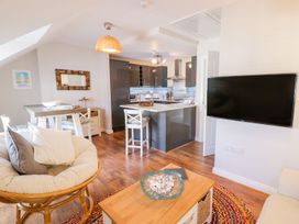 A living room with a round cushioned chair a wooden table and kitchen area at UpTown - Manhattan House in Llandudno