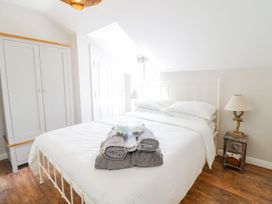 A bedroom with a bed with folded towels on it a wardrobe and a nightstand with a lamp at UpTown - Manhattan House in Llandudno