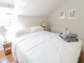 A bedroom with a white bed and gray towels on it with two lamps on wooden bedside tables at UpTown - Manhattan House in Llandudno