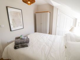 A bedroom with a bed white striped bedding folded towels wardrobe map on wall and a lamp at UpTown - Manhattan House in Llandudno