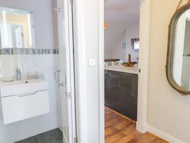 A bathroom sink and mirror beside a doorway leading to a dining area with wooden floors at UpTown - Manhattan House in Llandudno