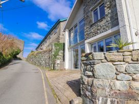 An exterior view of a house with a stone wall and road at Hafod Y Bryn in Harlech