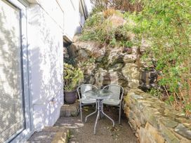 An outdoor area with a table and chairs next to a rock wall at Hafod Y Bryn Harlech