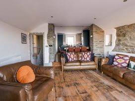 A living room with sofas and kitchen in the background at Island House in Aberaeron