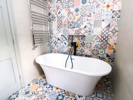 A bathroom featuring a bathtub and decorative wall tiles at Island House Aberaeron