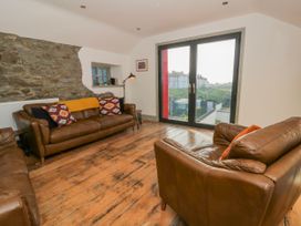 A living room with brown leather sofas and a large window at Island House in Aberaeron