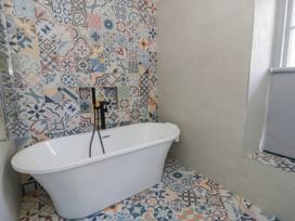 A bathroom with a bathtub and patterned tiles at Island House in Aberaeron