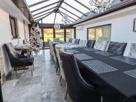 A conservatory with a long table and chairs at Brookway Lodge in Caerwys