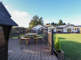 An outdoor area with a wooden deck and seating at Brookway Lodge in Caerwys
