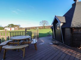 An outdoor seating area with a wooden table and benches at Brookway Lodge in Caerwys