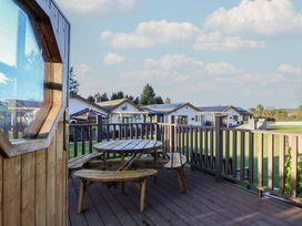 An outdoor deck with a table and chairs at Brookway Lodge in Caerwys