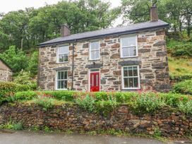 A stone house with red front door and flower beds at Ty Capel Bethania Nant Gwynant
