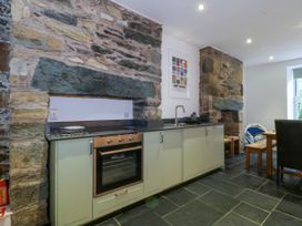 A kitchen with a stove and dining area at Ty Capel Bethania in Nant Gwynant
