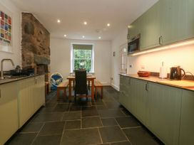 A kitchen with cabinets and dining table at Ty Capel Bethania Nant Gwynant