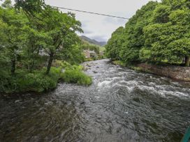 A river with trees and houses along the bank at Ty Capel Bethania in Nant Gwynant