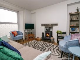 A living room with a sofa chairs a wood stove and a television at 7 New Street in Sedbergh