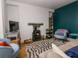 A living room with a fireplace television blue chairs and a patterned rug at 7 New Street in Sedbergh