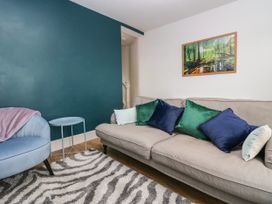 A living room with a beige sofa with colored cushions a blue armchair and a small round table at 7 New Street in Sedbergh