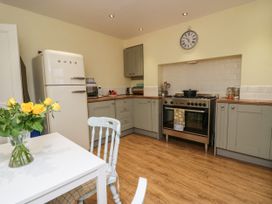 A kitchen with a white SMEG refrigerator gray cabinets a stainless steel stove and a table with yellow roses at 7 New Street in Sedbergh