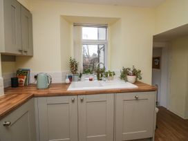 A kitchen with a sink under a window and potted plants on the countertop at 7 New Street in Sedbergh