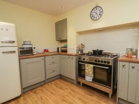 A kitchen with grey cabinets a stove a refrigerator and kitchen appliances at 7 New Street in Sedbergh
