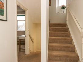 A carpeted staircase with a handrail and a window with flowers in a vase at 7 New Street in Sedbergh