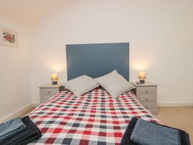A bedroom with a double bed with checkered bedspread pillows two bedside tables with lamps and folded towels at 7 New Street in Sedbergh