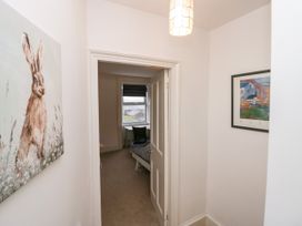 A hallway with a rabbit painting on the left wall and a framed artwork on the right with a partially open door leading to a bedroom at 7 New Street in Sedbergh
