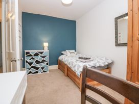 A bedroom with a single bed next to a blue accent wall and a patterned chest of drawers at 7 New Street in Sedbergh