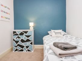 A bedroom with a bed with patterned bedding and folded towels next to a geometric patterned chest of drawers with a lamp on it at 7 New Street in Sedbergh