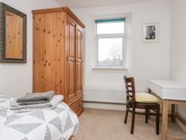 A bedroom with a wooden wardrobe a white desk with a wooden chair and a bed with folded towels at 7 New Street in Sedbergh