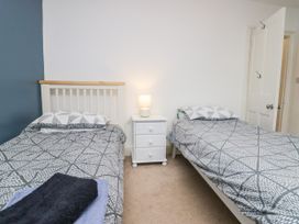 A bedroom with two single beds a white nightstand with a lamp between the beds and a door in the background at 7 New Street in Sedbergh